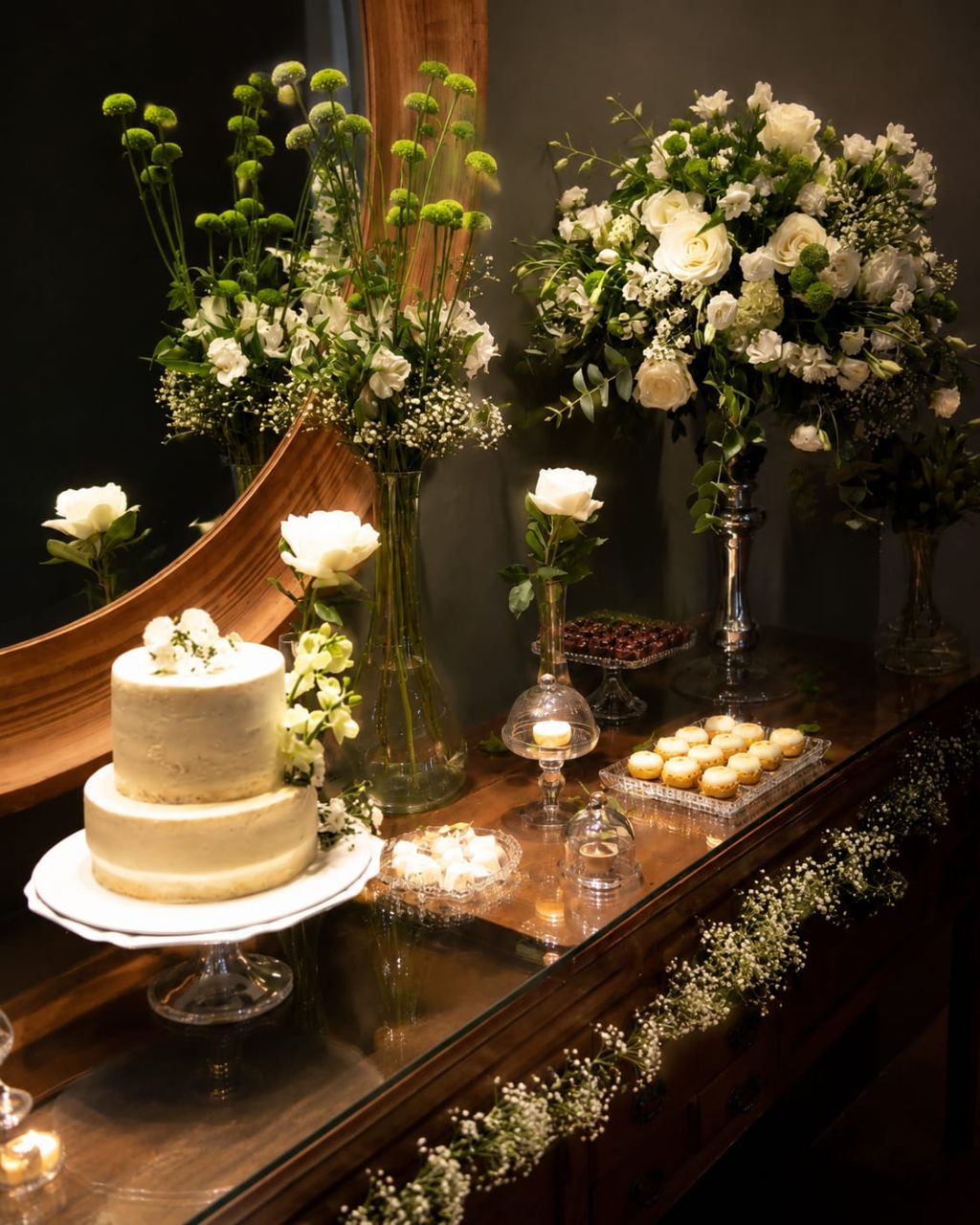 Mesa de doces decorada com bolo e arranjos florais brancos